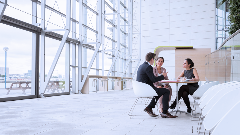 Three people in a meeting sat at a table