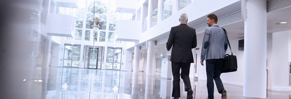Two men walking down atrium corridor