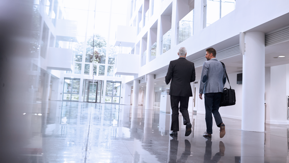 Two men walking down atrium corridor